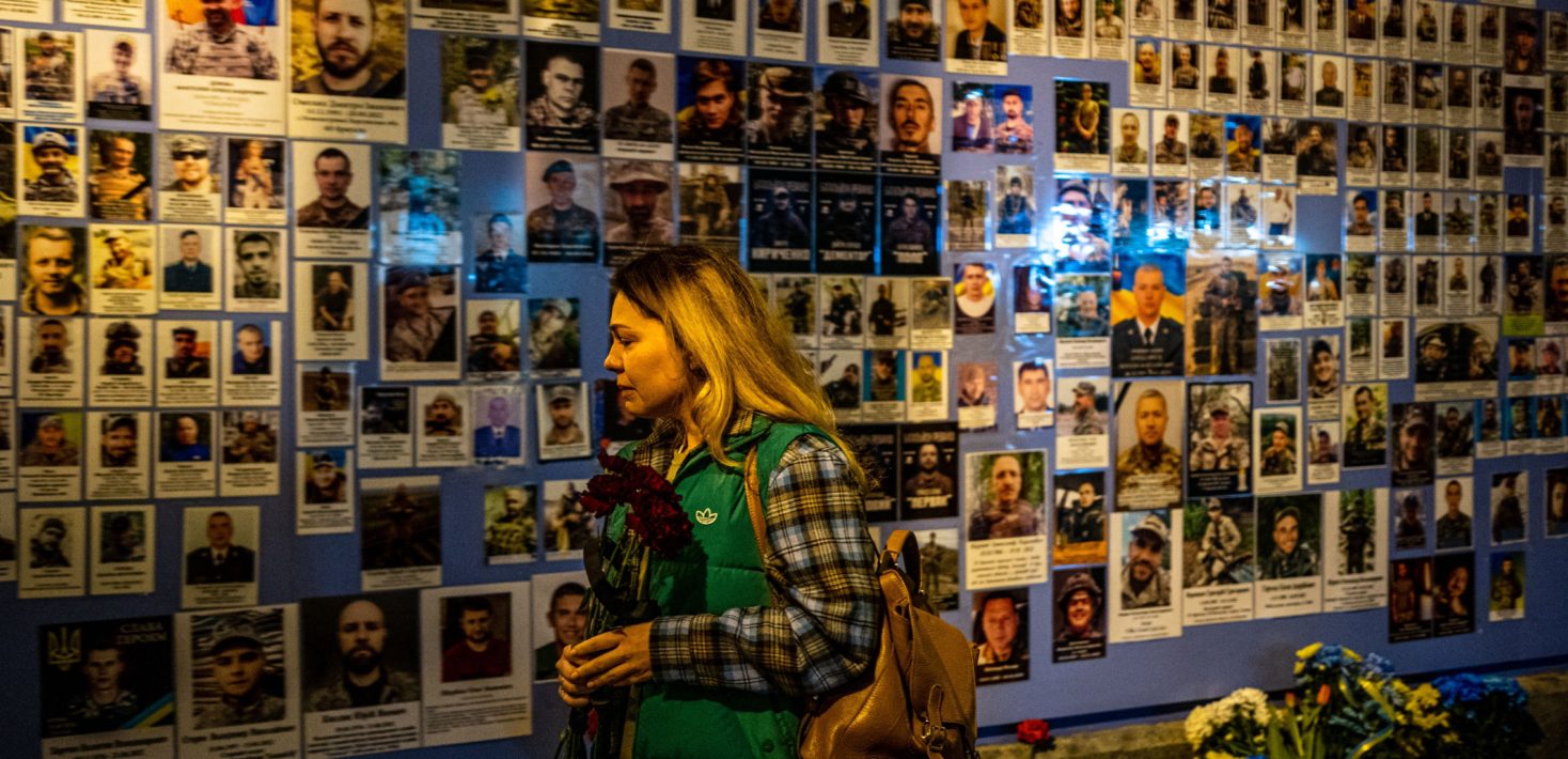 Женщина реагирует на фотографии, выставленные на Стене памяти павших защитников Украины во время вторжения России в Украину в Киеве 24 февраля 2023 года, в первую годовщину войны.